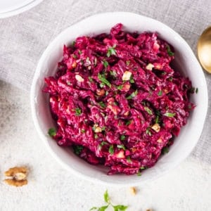 beet-salad-in-a-white-bowl-on-a-towel-with-a-spoon