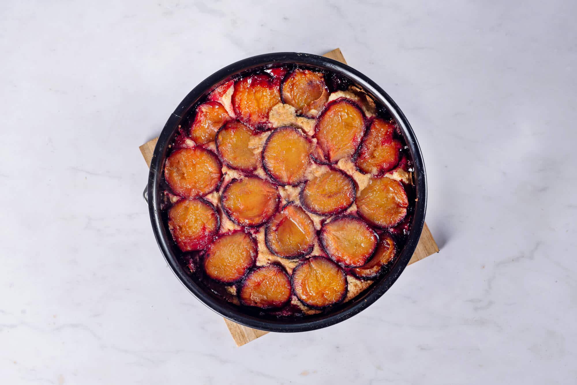 baked-plum-cake-in-a-baking-pan-on-a-wooden-board