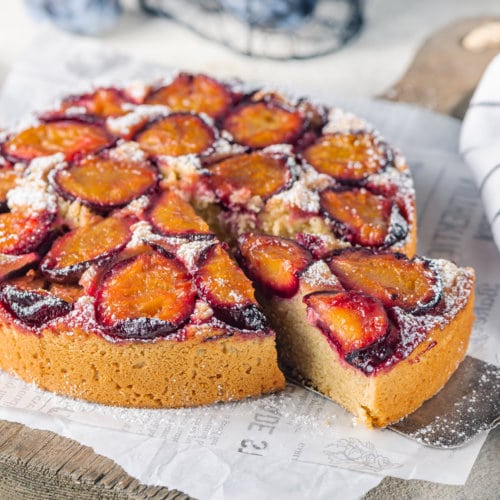 plum cake on white paper with a slice cut.