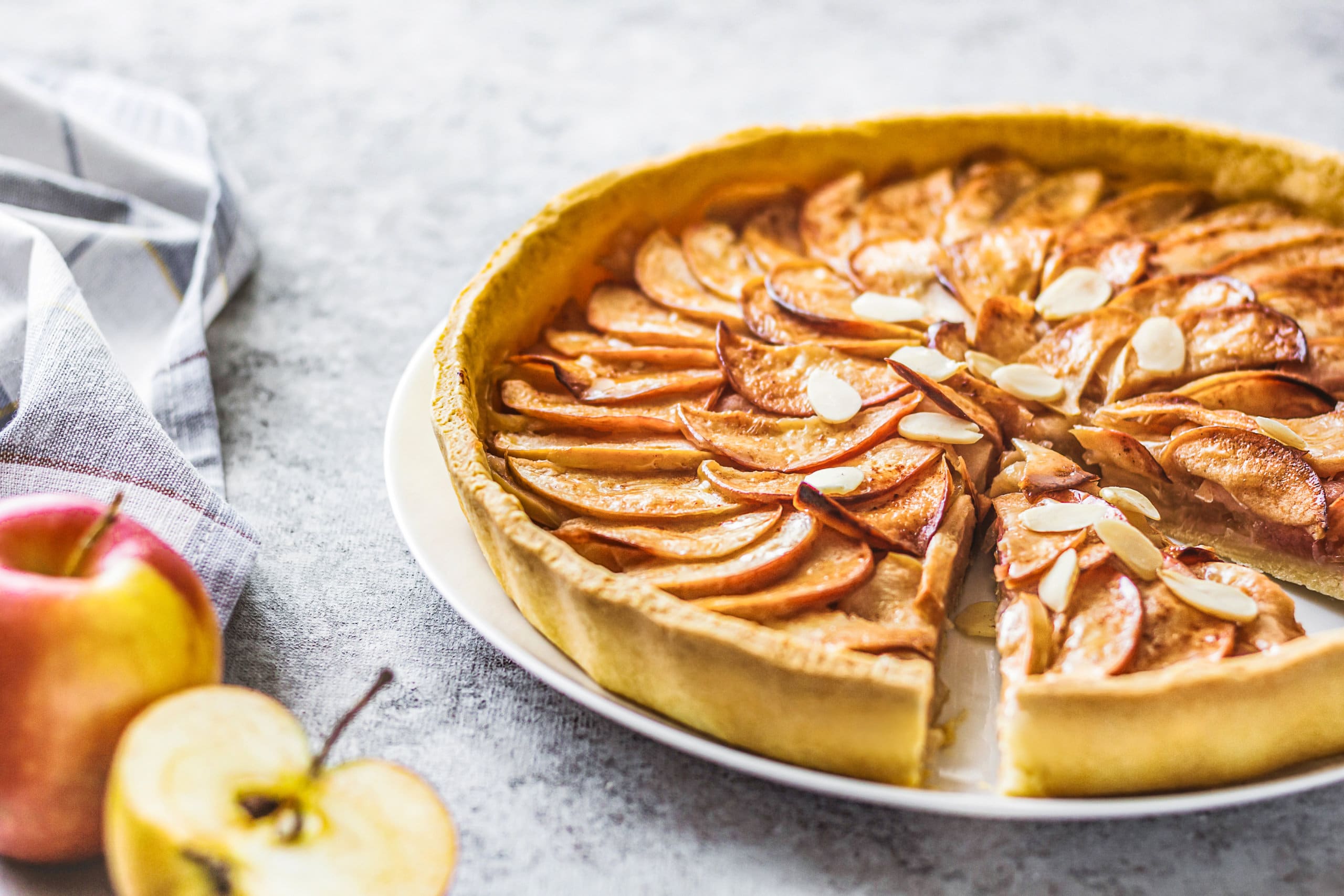 apple tart recipe on a white plate with a halved apple on the side.