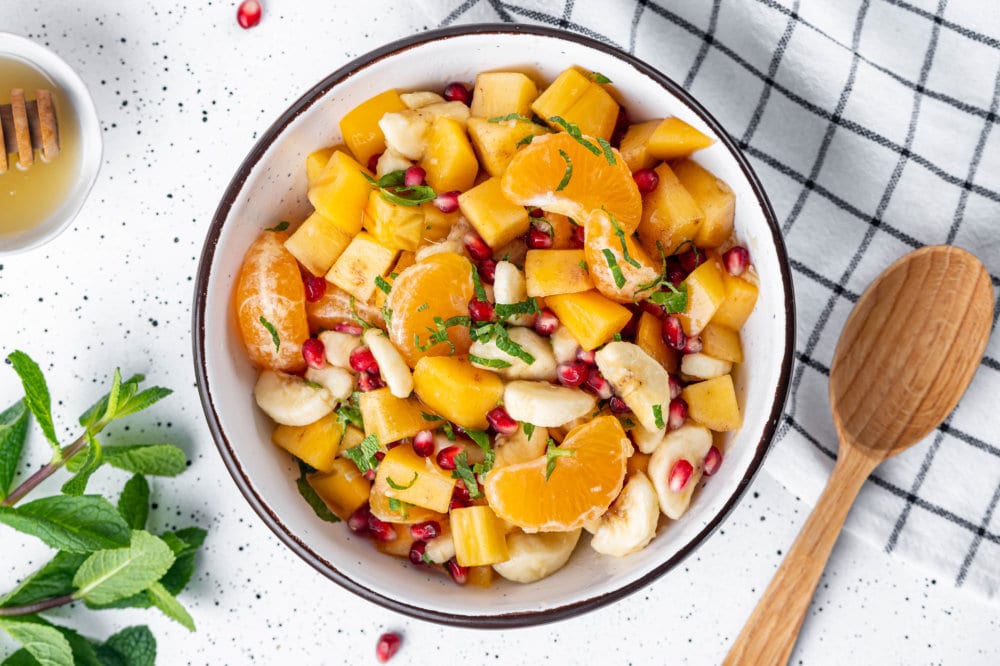 persimmon-fruit-salad-in-a-bowl-with-a-wooden-spoon-on-the-side-on-a-towel