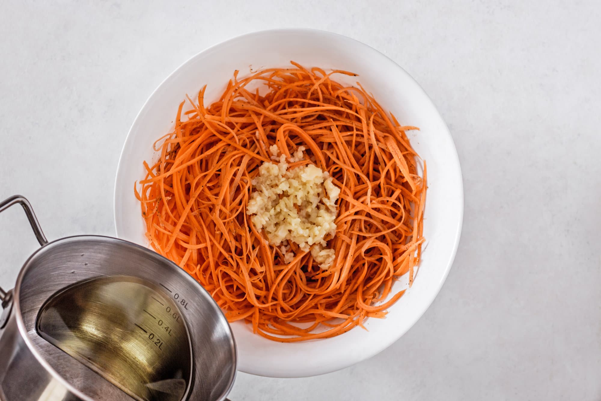 carrots-and-spices-in-a-white-bowl-being-combined-with-grape-seed-oil-and-garlic