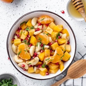 persimmon-fruit-salad-in-a-bowl-with-a-wooden-spoon-on-the-side-on-a-towel