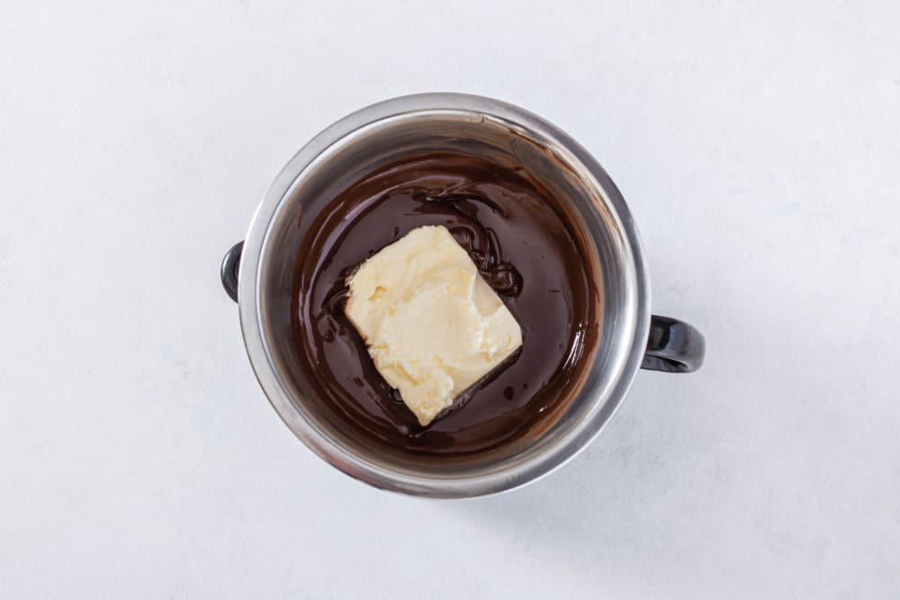 chocolate-glaze-being-mixed-with-butter-in-a-silver-bowl