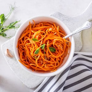 korean-carrot-salad-in-a-white-bowl-on-a-grey-board-with-a-fork