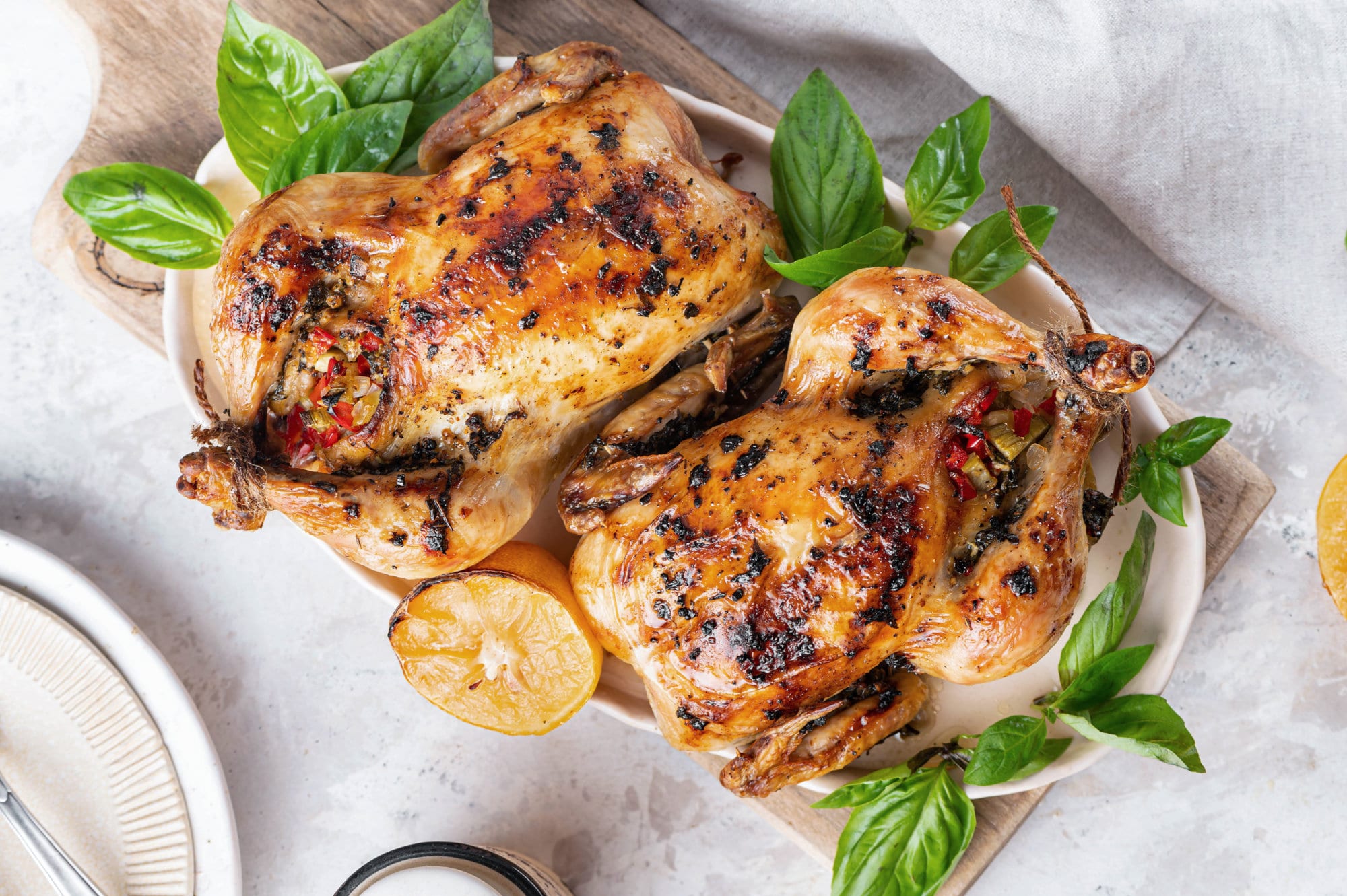 cornish-hens-on-a-white-plate-with-basil-on-a-wooden-board