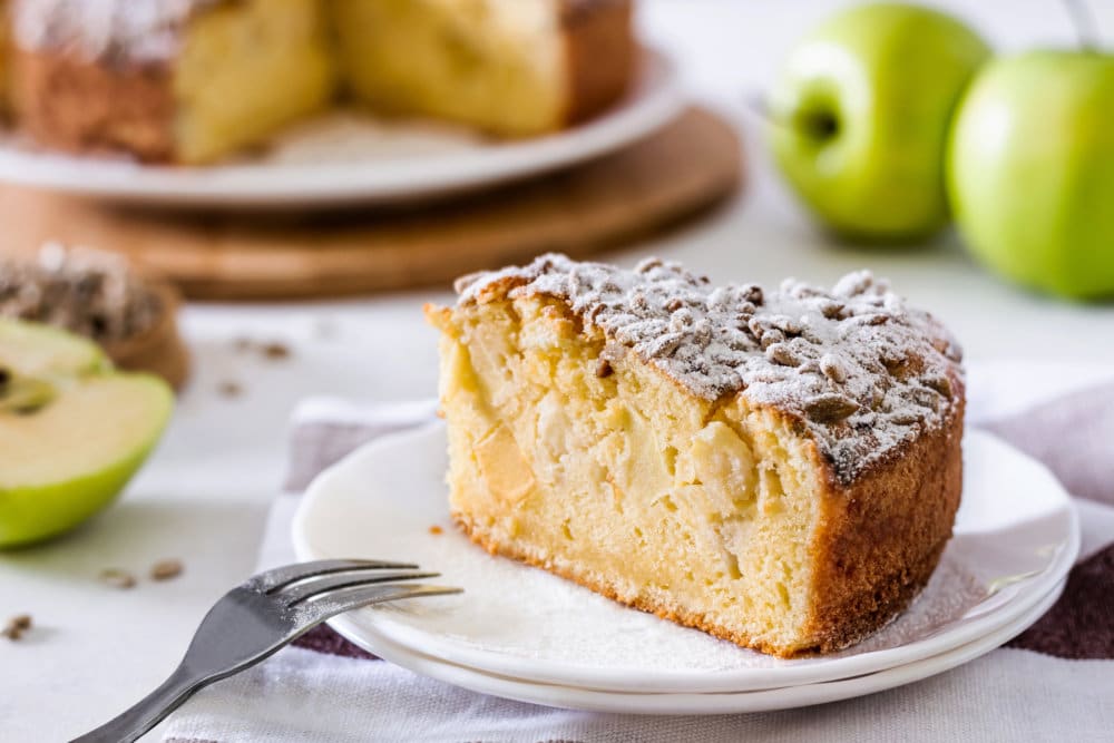 a slice of apple cake on a white plate with a fork.