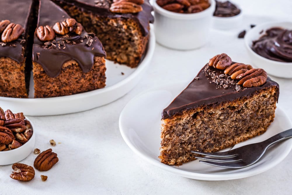 pecan torte slice on a white plate with a fork.