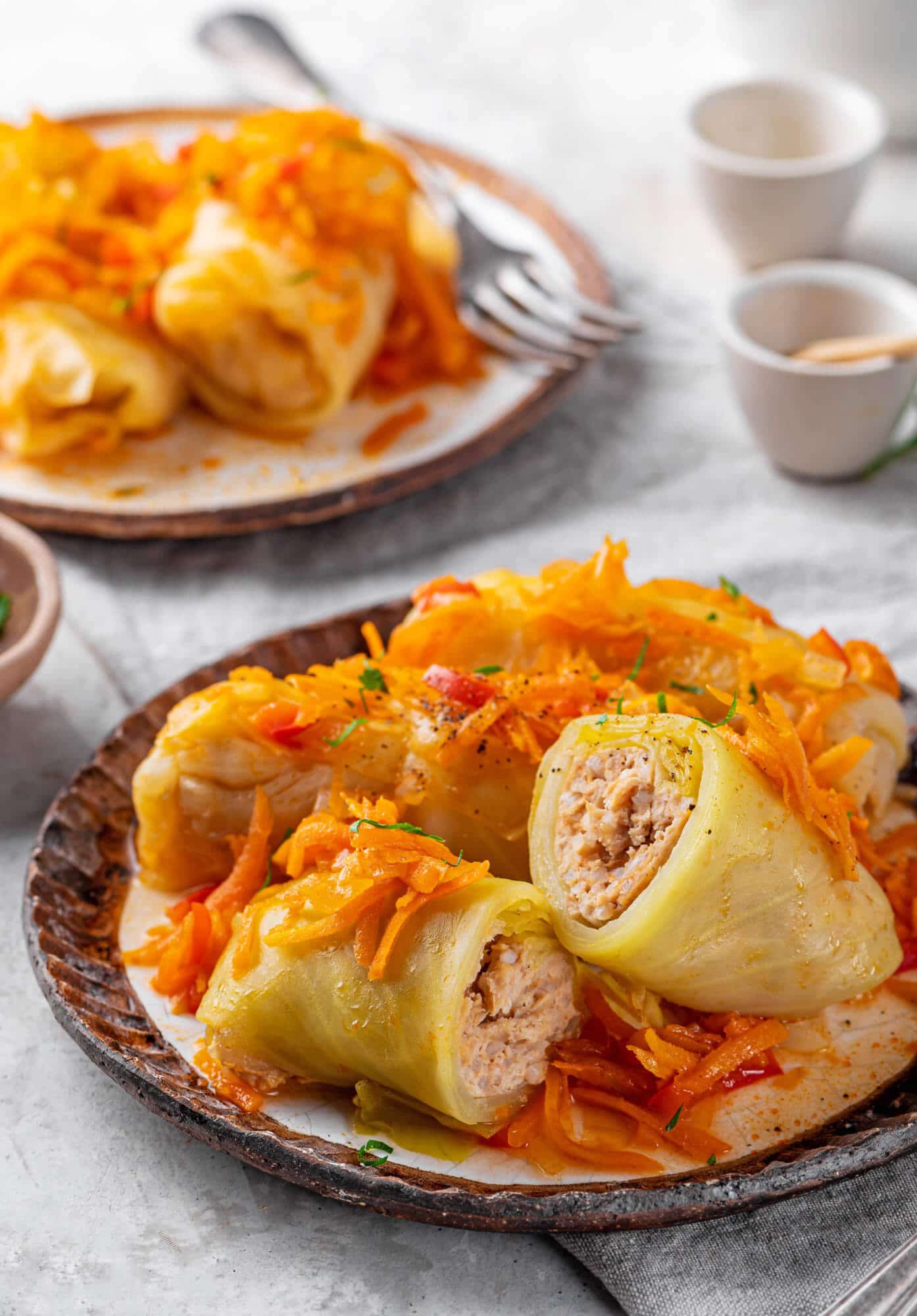 Halved cabbage rolls and vegetable sauce on a brown plate ready to serve.