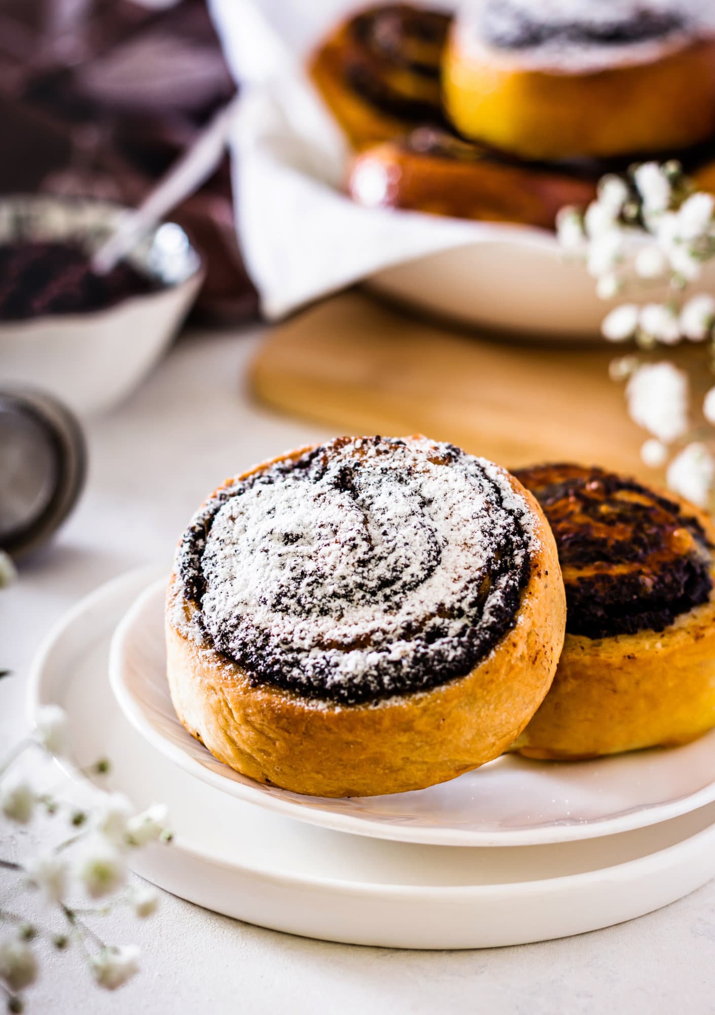 Pinwheel cookies on a white plate topped with powdered sugar. 