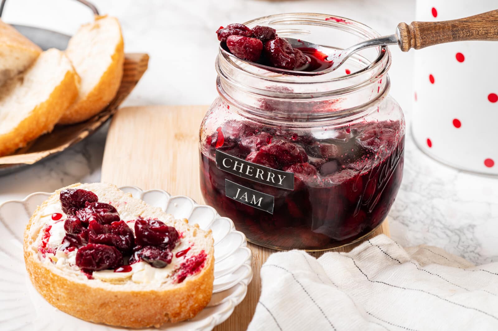 Cherry jam in a jar and on bread.