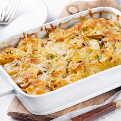 scalloped-potatoes-in-baking-dish-on-wooden-board-with-spoon