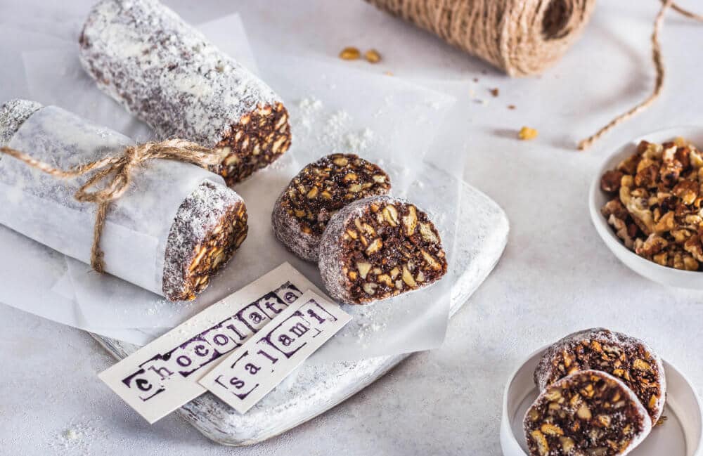 chocolate salami slices on a white board with parchment paper with paper labels.