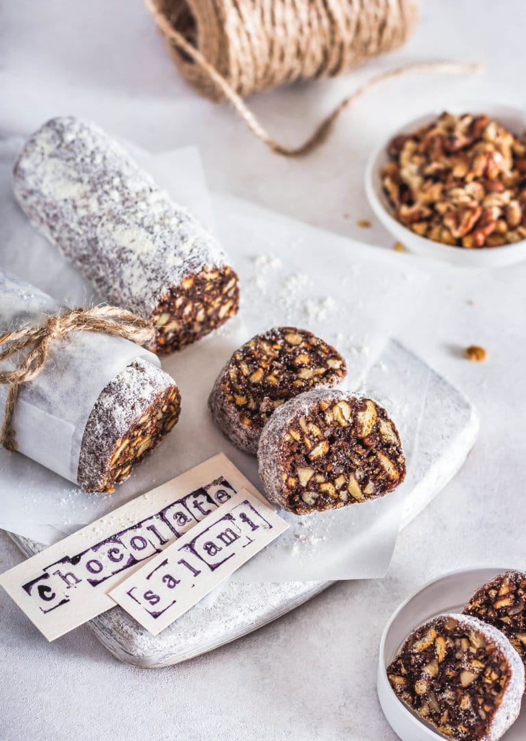 Chocolate salami sliced on a white board with paper labels.