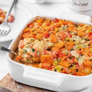 Fish and veggie casserole in a large baking dish with a spoon.