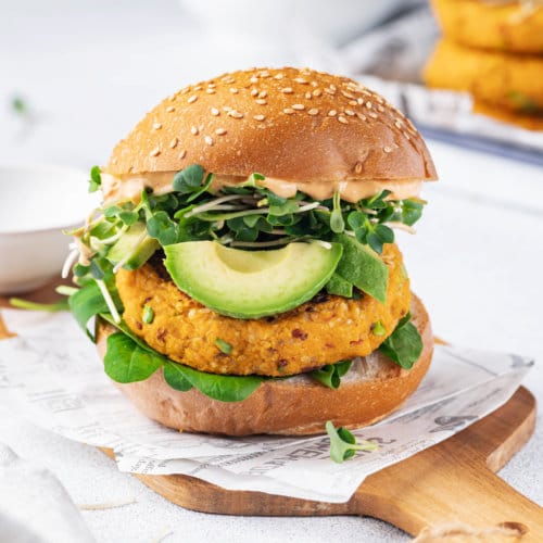 a burger with a sweet potato patty on parchment and on a wooden board.