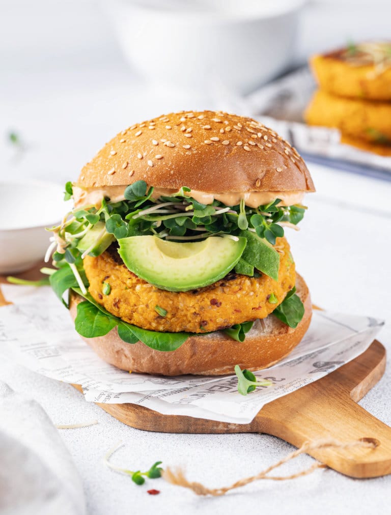 a burger with a sweet potato patty on parchment and on a wooden board.