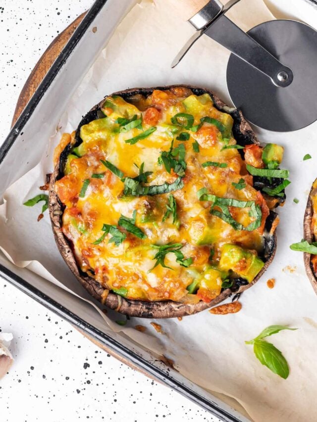 mushroom pizza in a baking tray with a pizza cutter on the side.