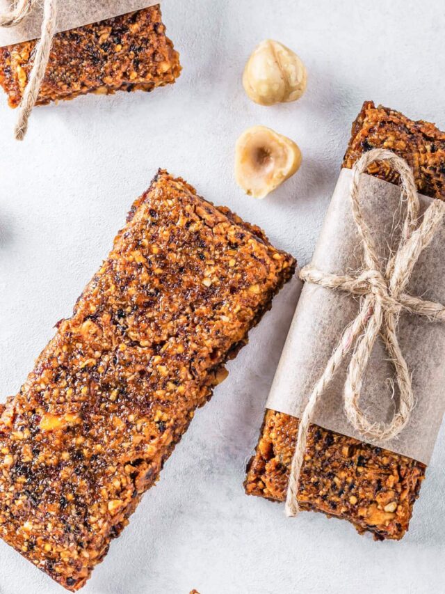 dried fruit and nut bars one wrapped in brown paper with brown twine with a macadamia nut on the side.