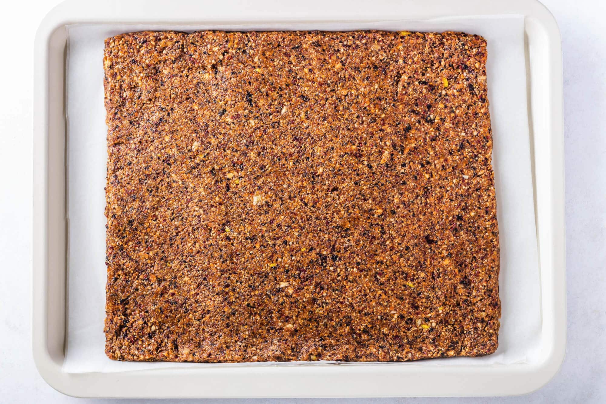 Gluten-Free Dried Fruit Bars with Nuts and Dates on The Go Dried fruit and nut bar spread out in a big square on a baking tray.