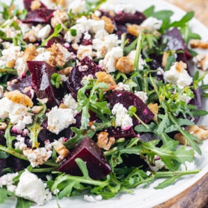 beet-salad-on-a-white-plate-and-wooden-board-with-cheese-and-arugula