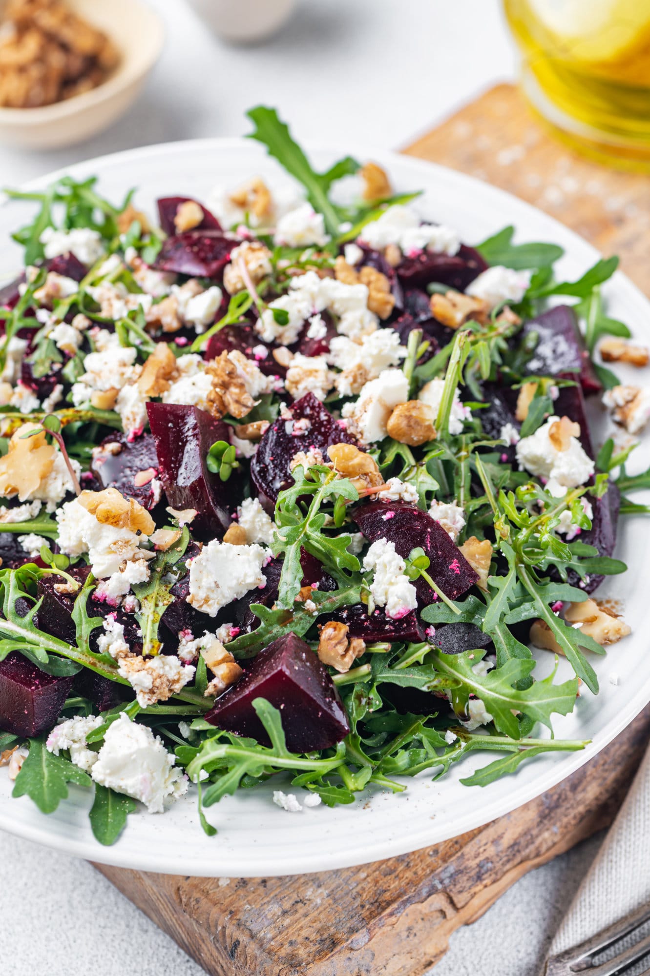 beet-salad-on-a-white-plate-and-wooden-board-with-cheese-and-arugula