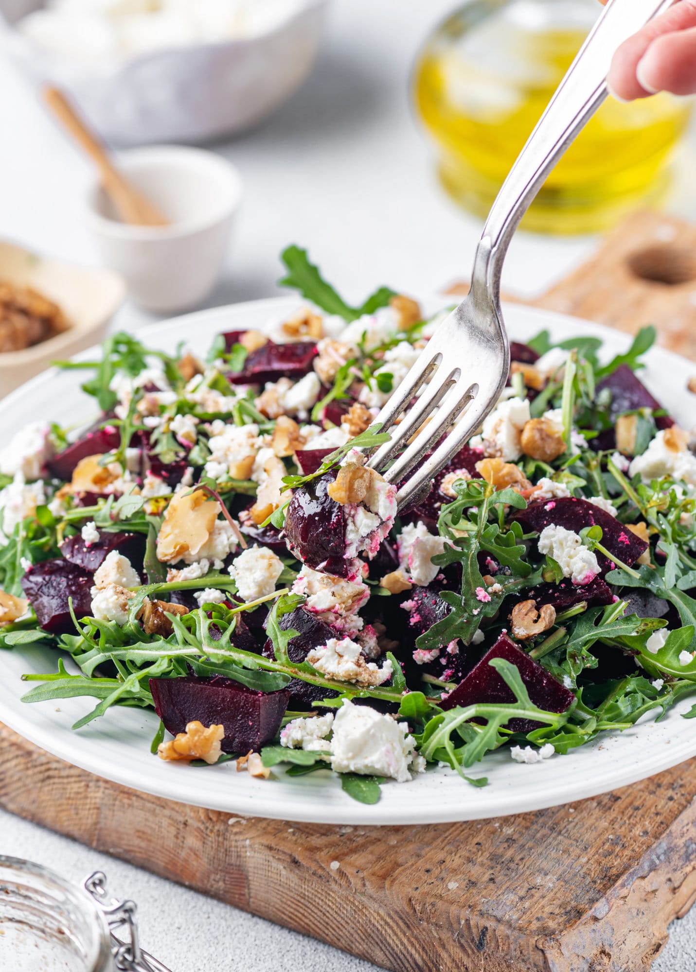 beet-salad-on-a-white-plate-and-wooden-board-with-cheese-and-arugula-and-fork