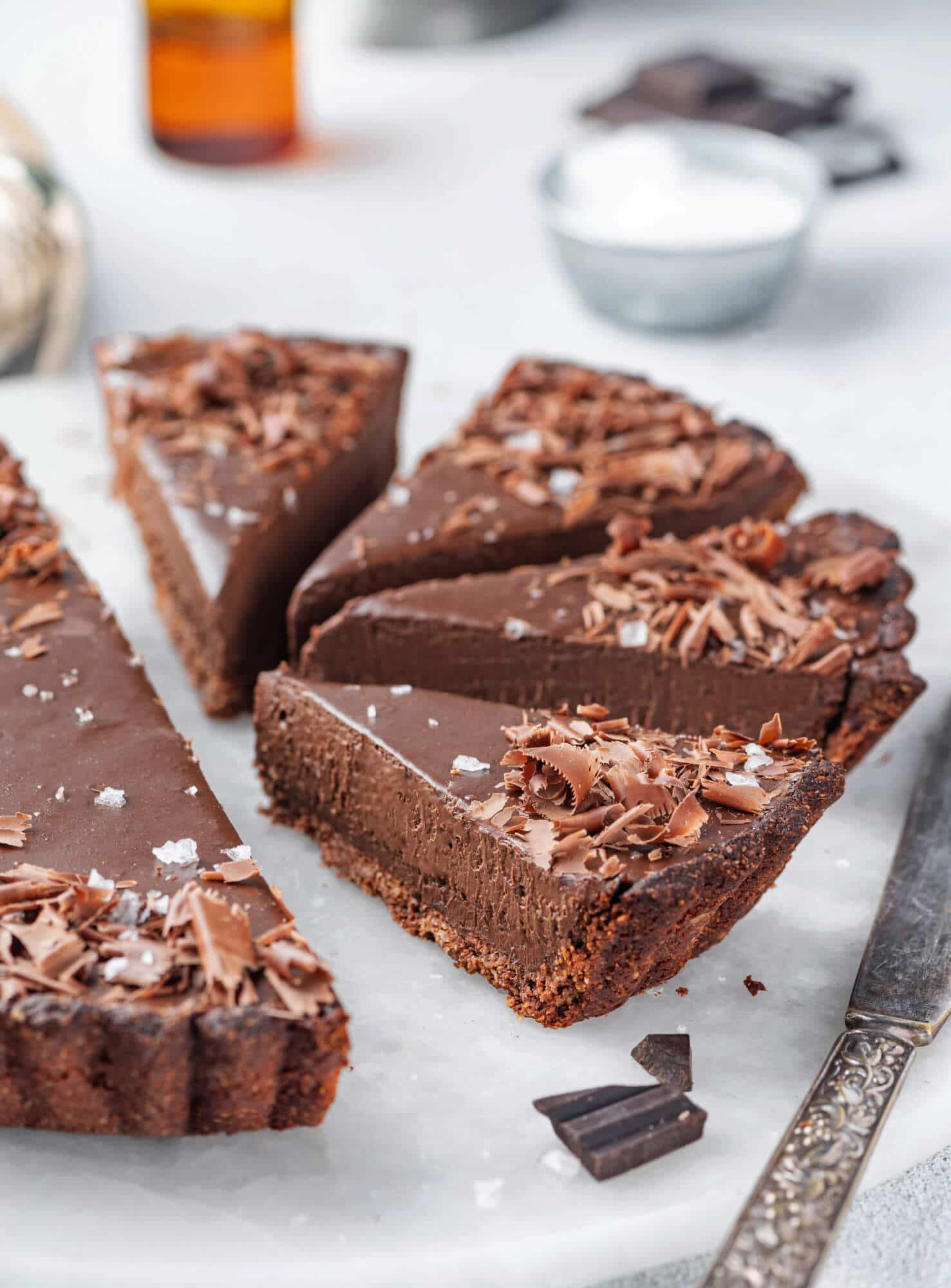 Sliced chocolate tart on a white cutting board.