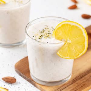 a glass of lemon smoothie with a lemon wedge on the rim with hemp seeds sprinkled on top.