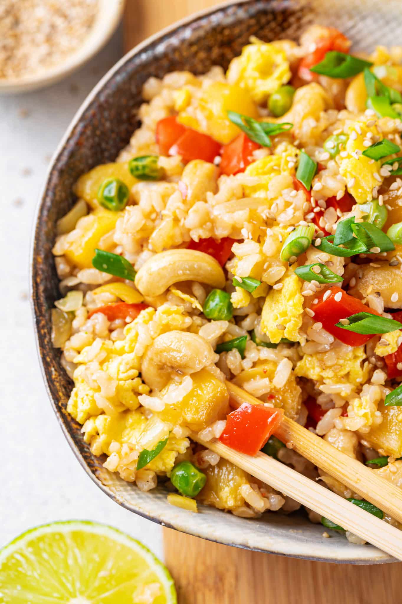 pineapple fried rice with cashews and scallions in a brown bowl.