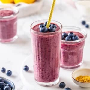 blueberry blended smoothie in three glasses and straws.