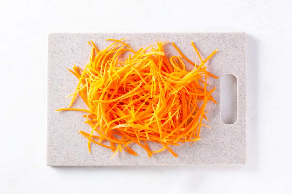 a cutting board with shredded carrots.