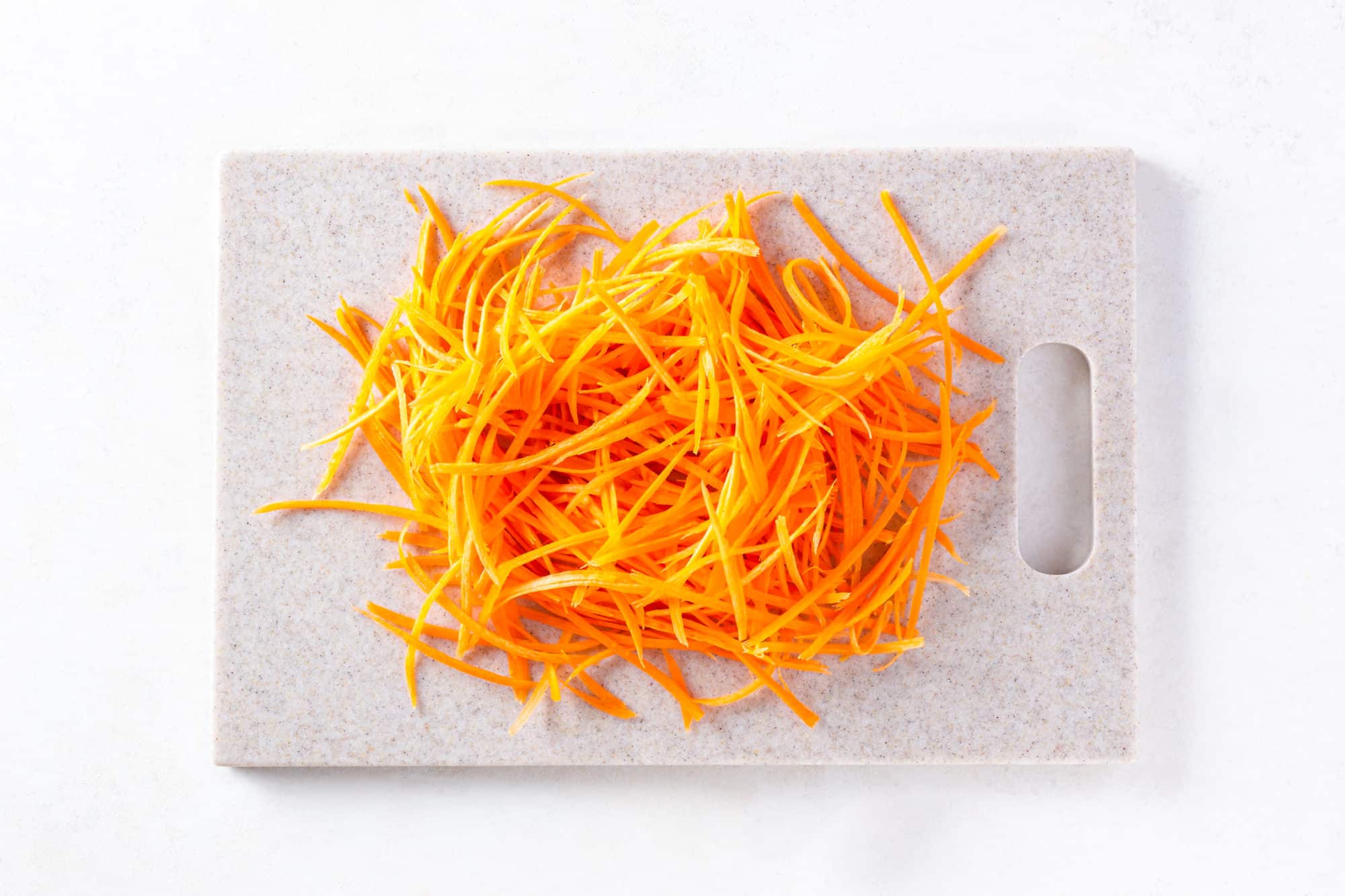 A cutting board with shredded carrots.