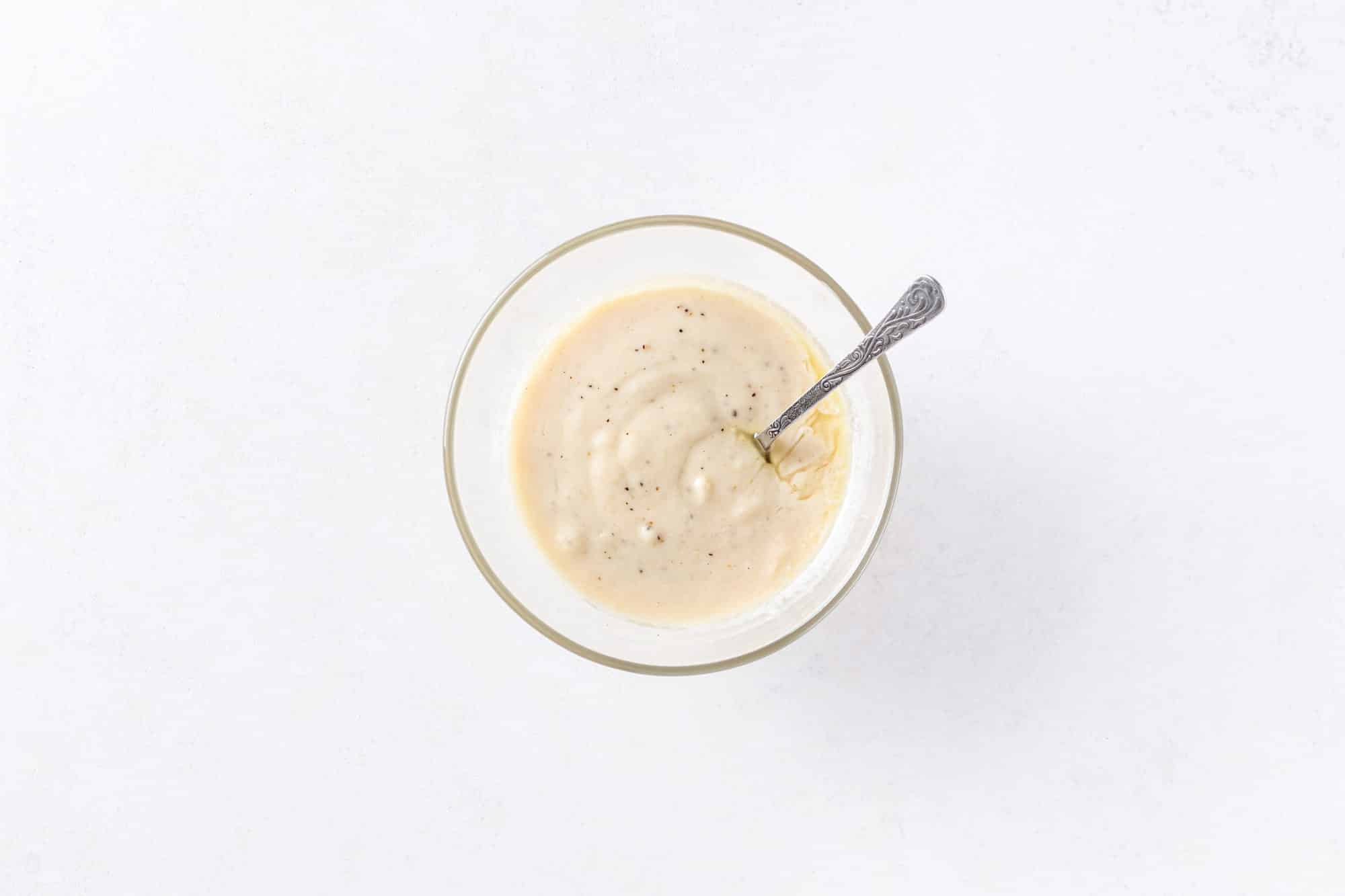 Creamy tahini dressing in a bowl with a spoon.