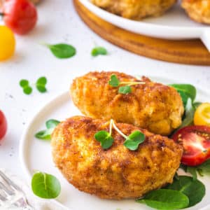 a white plate with prepared stuffed chicken and microgreens.