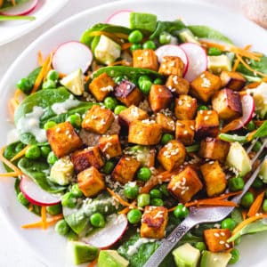 a white plate with tofu salad and a fork.