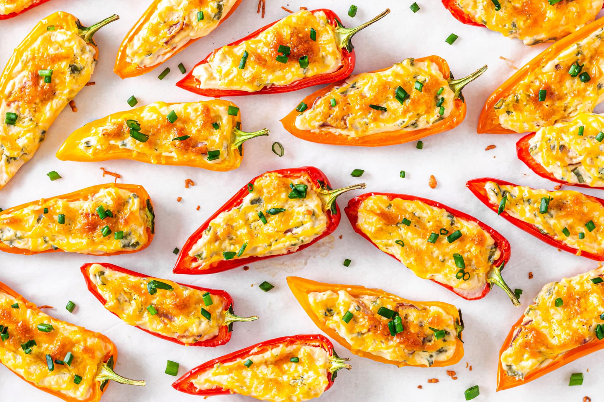 Freshly baked mini bell peppers stuffed with cream cheese and topped with cheese with green onions on top.