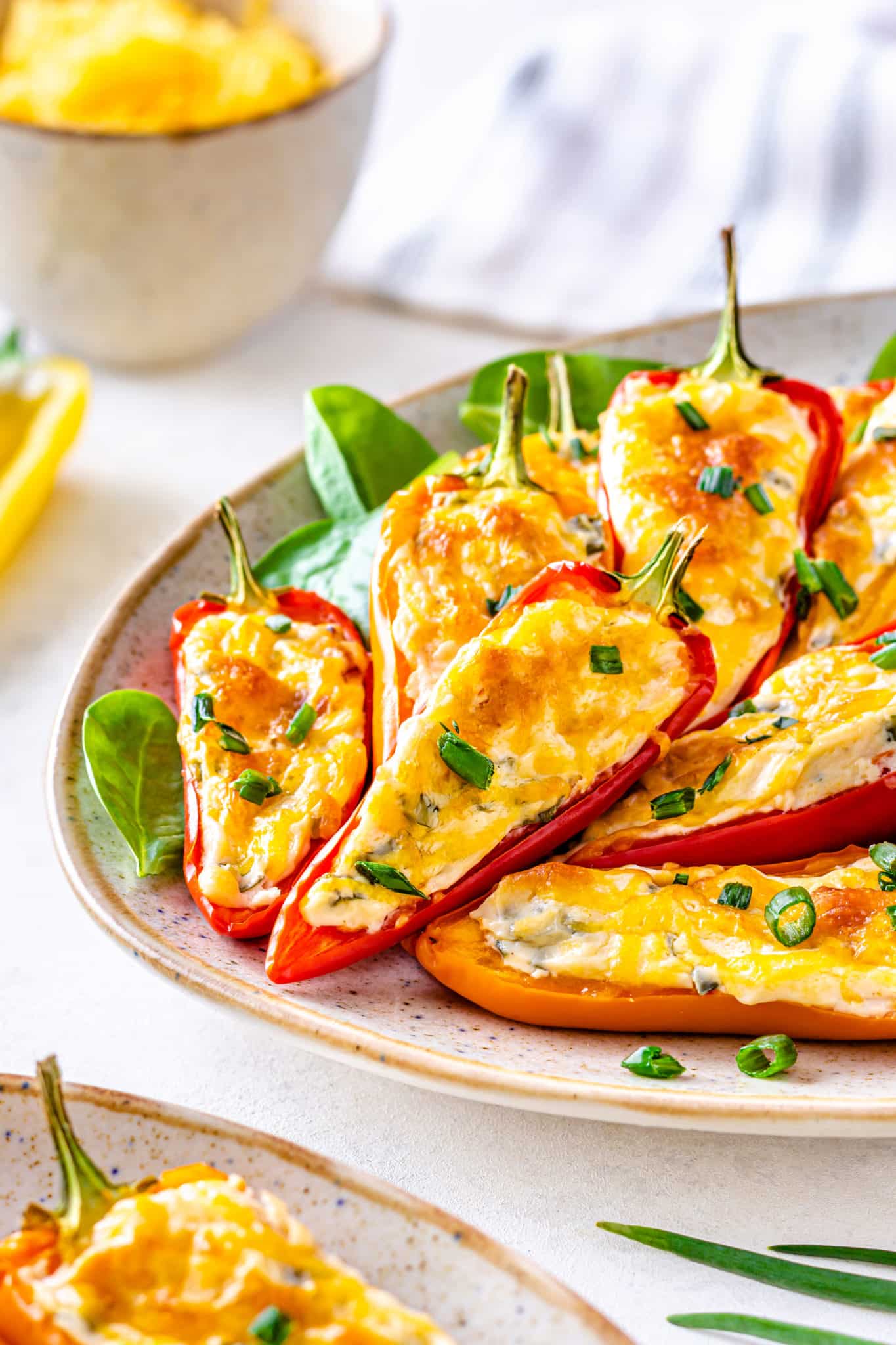 cream cheese stuffed bell peppers on a plate with garnish behind them