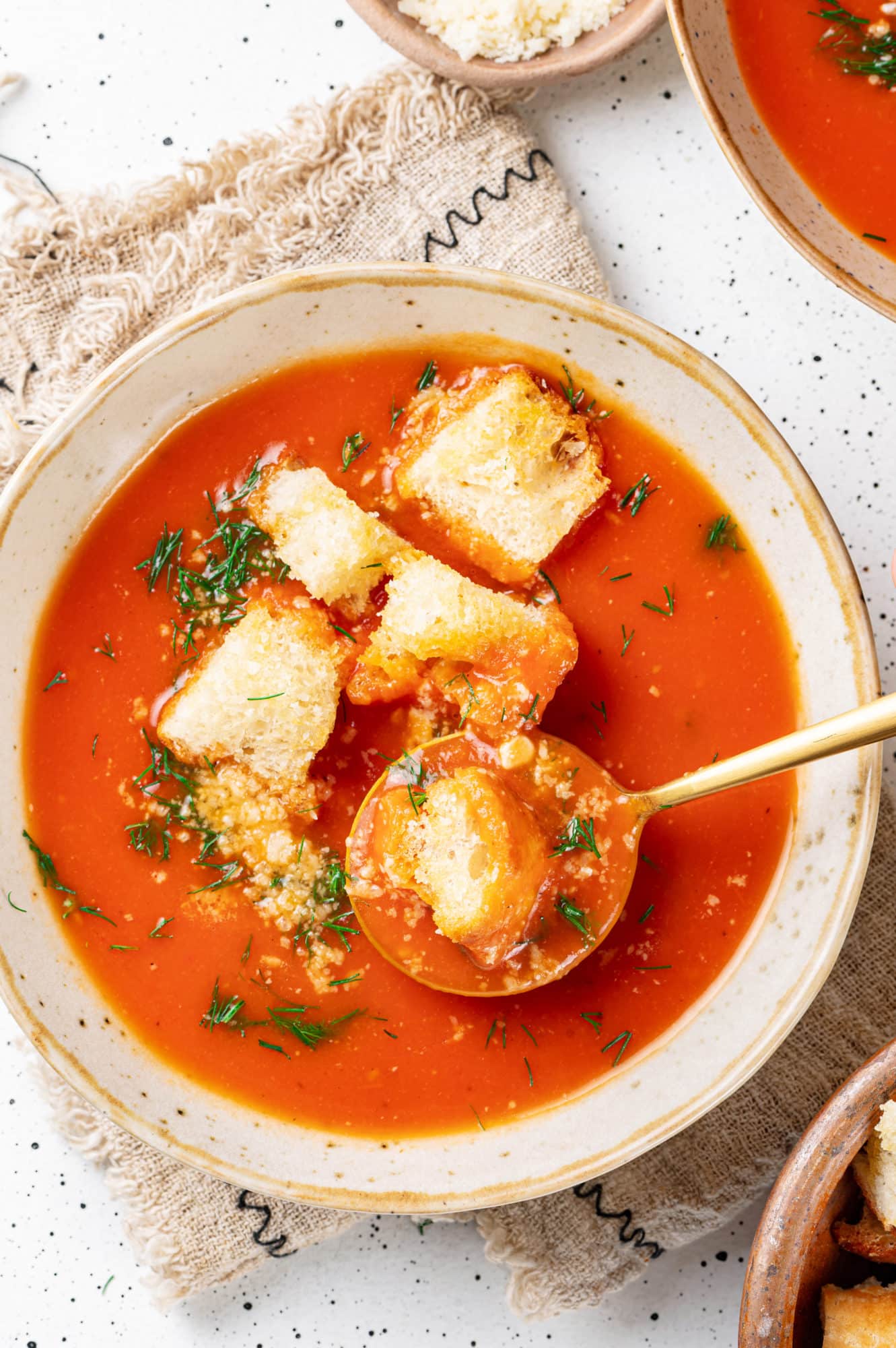 a bowl of tomato soup with croutons on top and croutons with parsley on top.