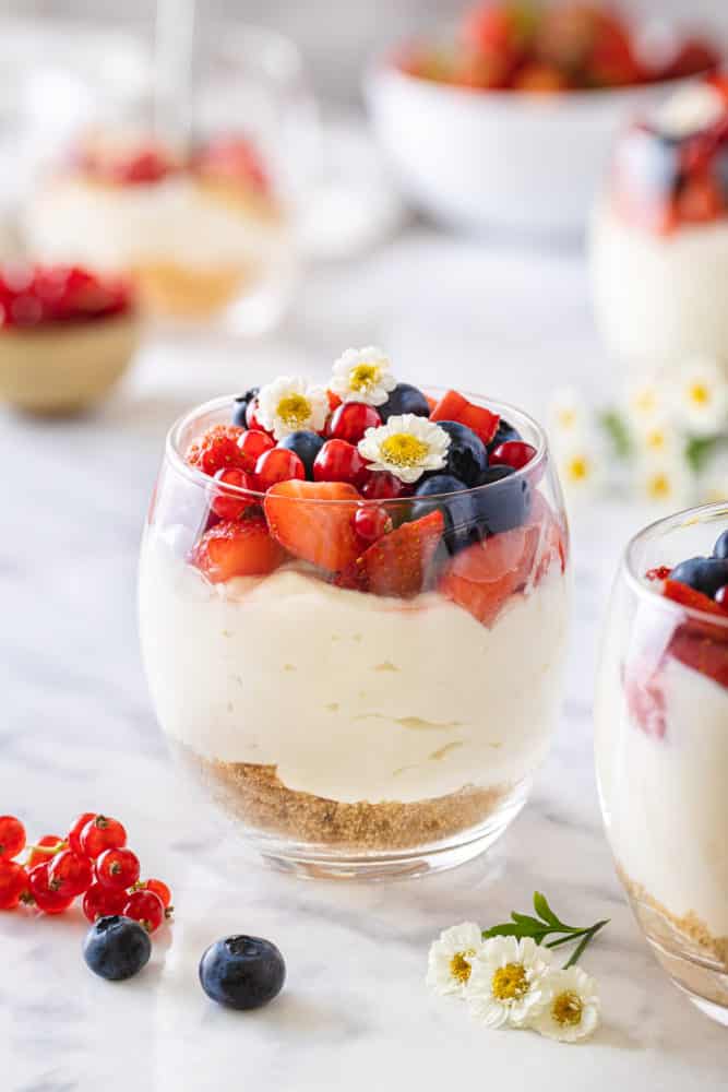 a glass filled with cheesecake with berries on top and a graham cracker base.