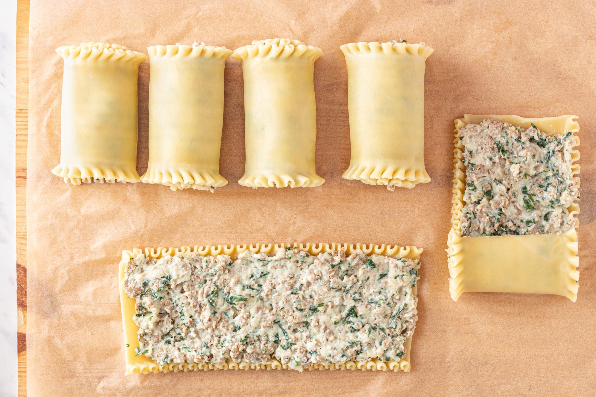 lasagna-pasta-being-rolled-with-meat-filling-inside-on-parchment-paper