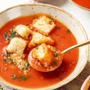 tomato soup in a bowl with croutons and a spoon.
