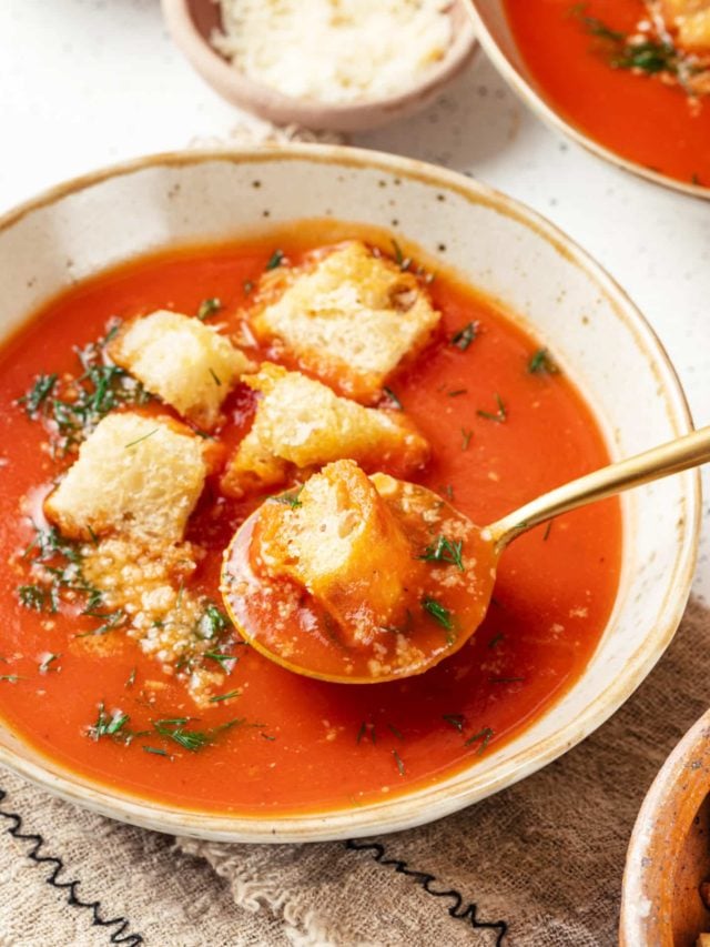 tomato soup in a bowl with croutons and a spoon.