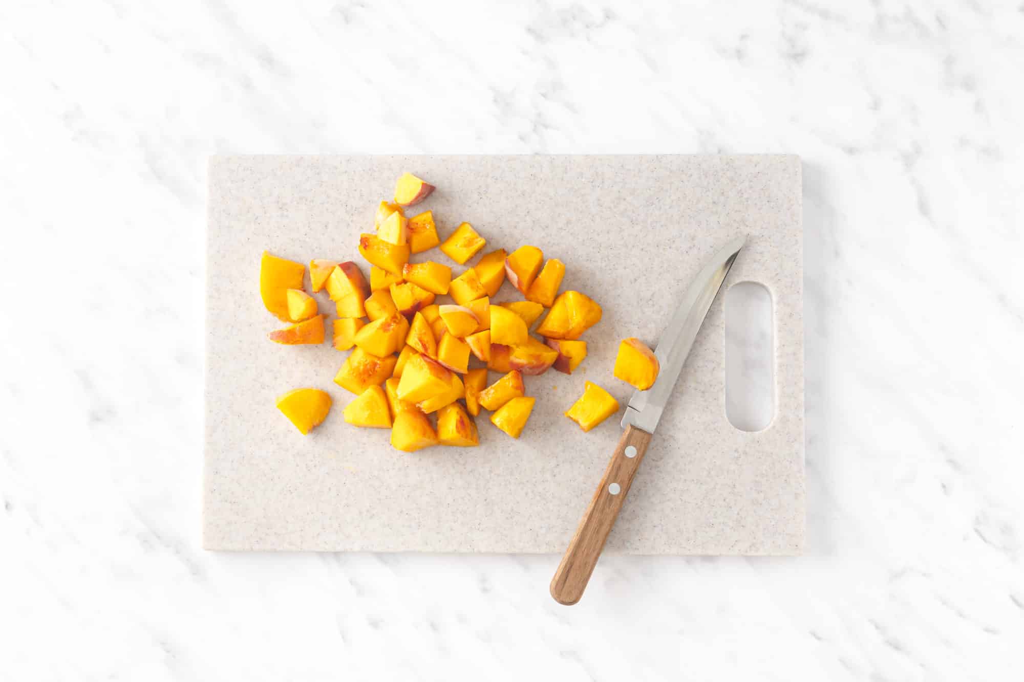 chopped peaches on a chopping board with a knife beside them