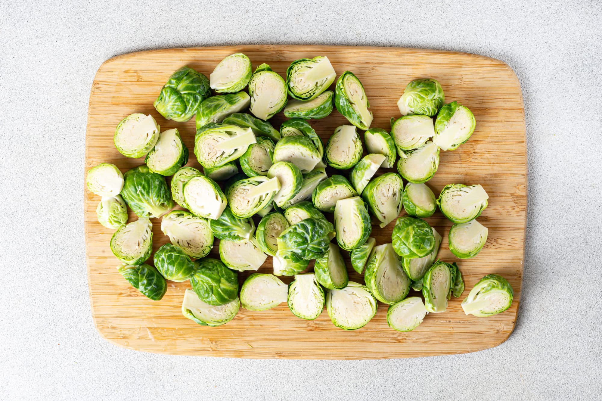 a wooden cutting board with chopped brussels sprouts on it.