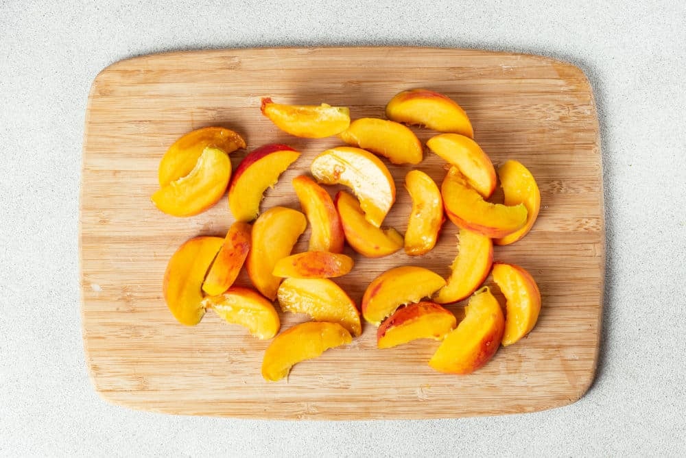 peach slices on a wooden board.