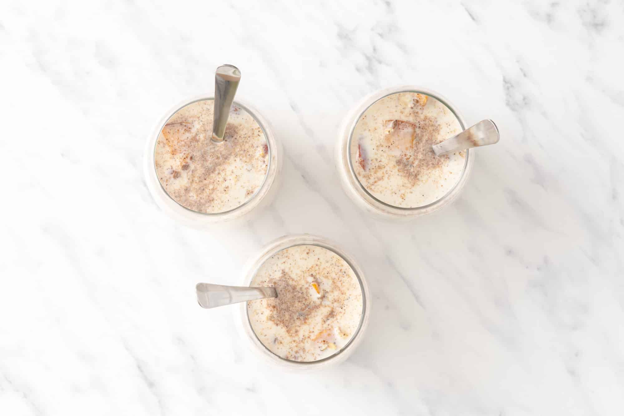 three glasses of overnight oats with spoons in them photographed from above