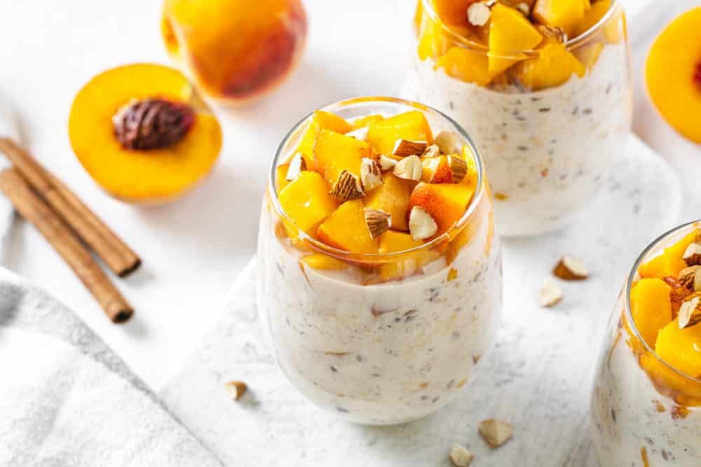 peach-overnight-oats-on-a-marble-board-with-cinnamon-and-peaches-in-the-background