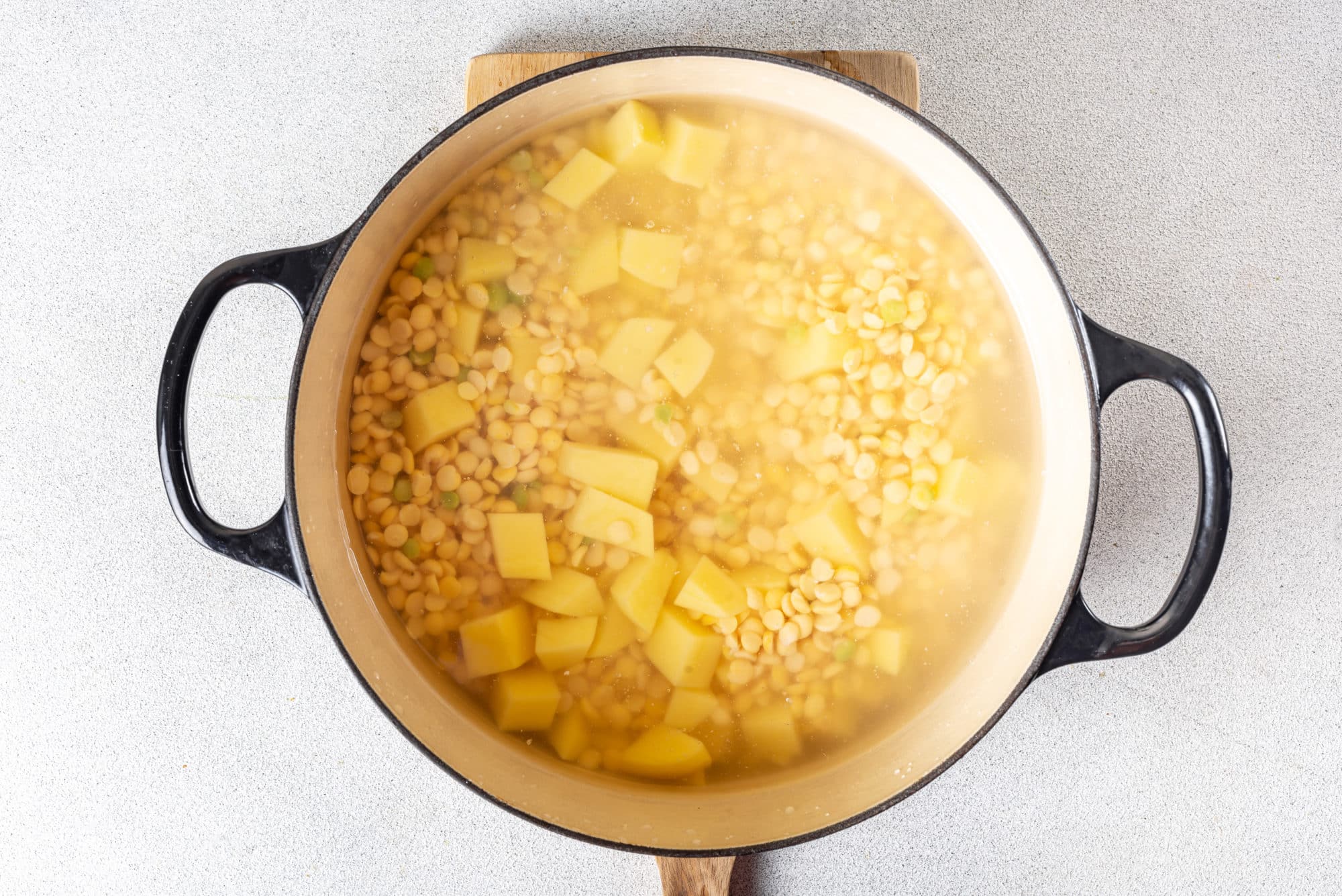 split-peas-and-potatoes-in-a-soup-pot-with-water-on-a-wooden-board