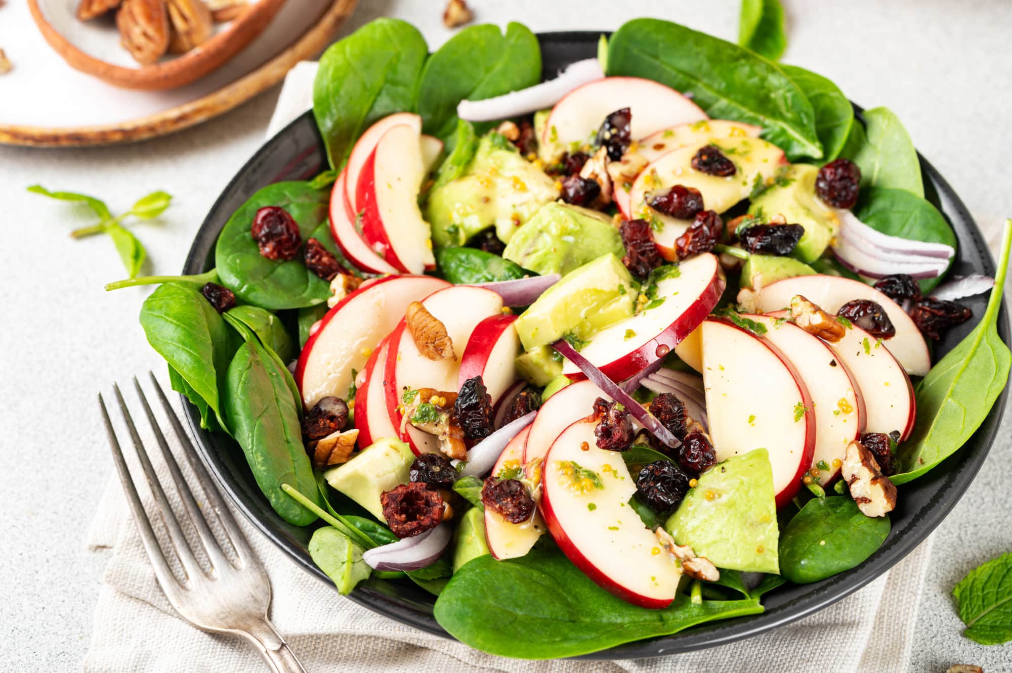 A bowl of apple, spinach, avocado salad.